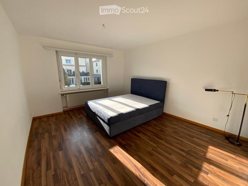 Single bed, wooden floor, window with city view, radiator