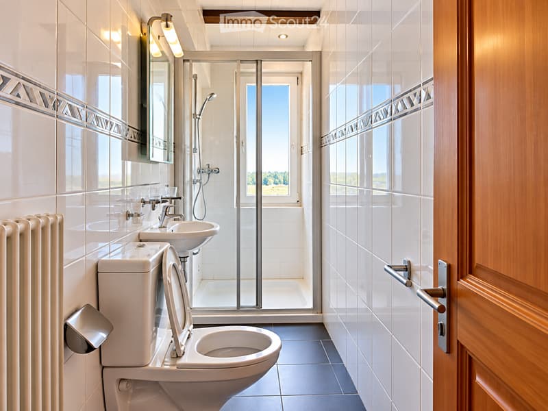 Modern bathroom with white tiles, a toilet, sink, shower, and a large window offering a view of the outdoors.
