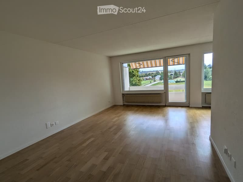 Empty room with wooden flooring, large windows, and radiators. No furniture or equipment present.