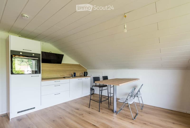 Modern kitchen with white cabinets, wooden countertops, and a dining area featuring a table and chairs.