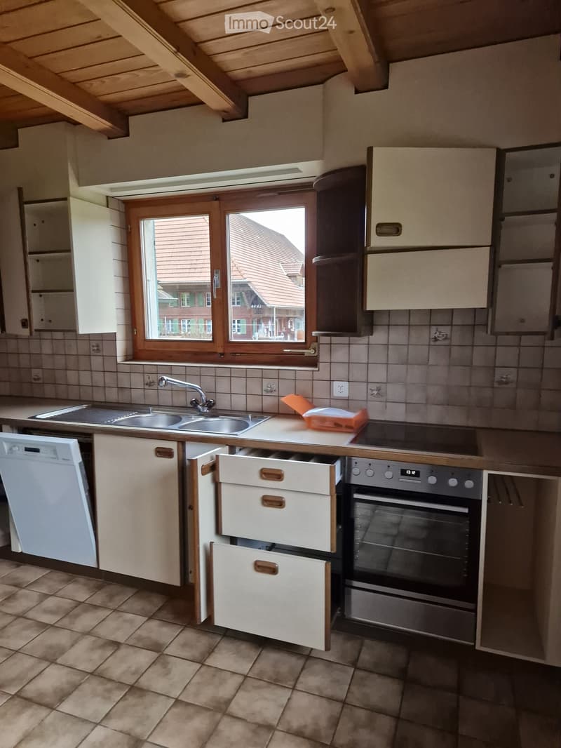 Kitchen with tiled walls, wooden cabinets, stainless steel sink, oven, dishwasher, and countertop items.