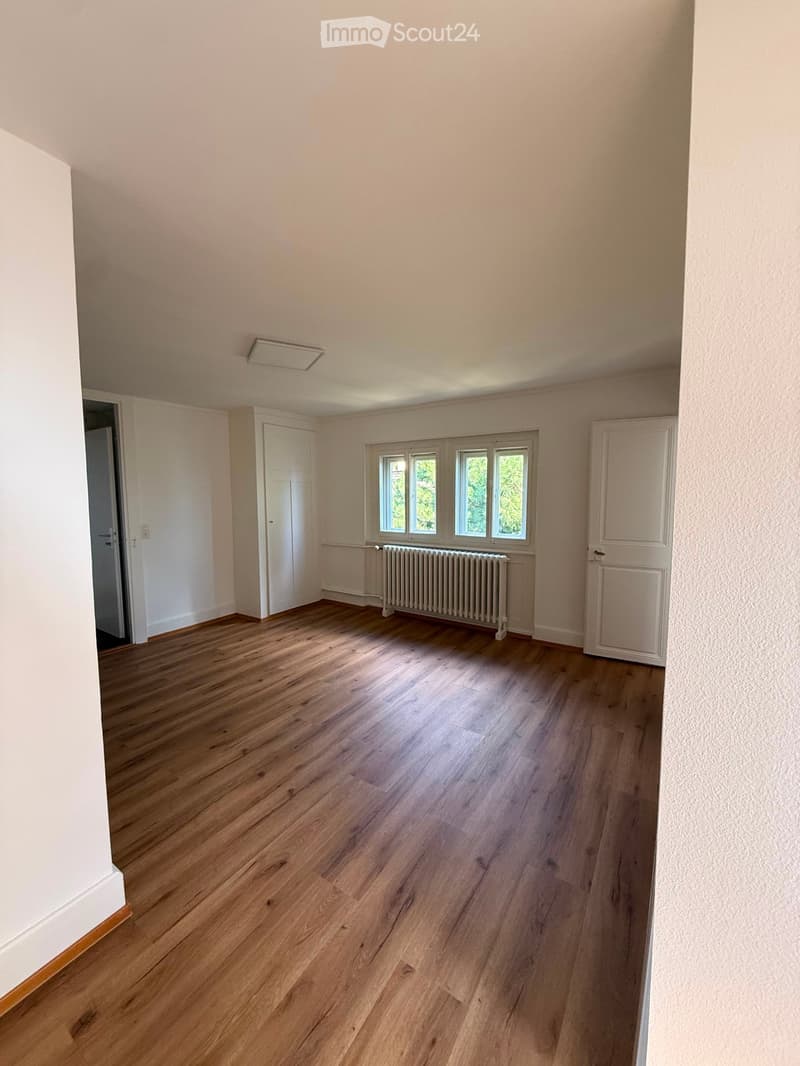 Empty room with wooden flooring, white walls, and large windows. No furniture or equipment present.