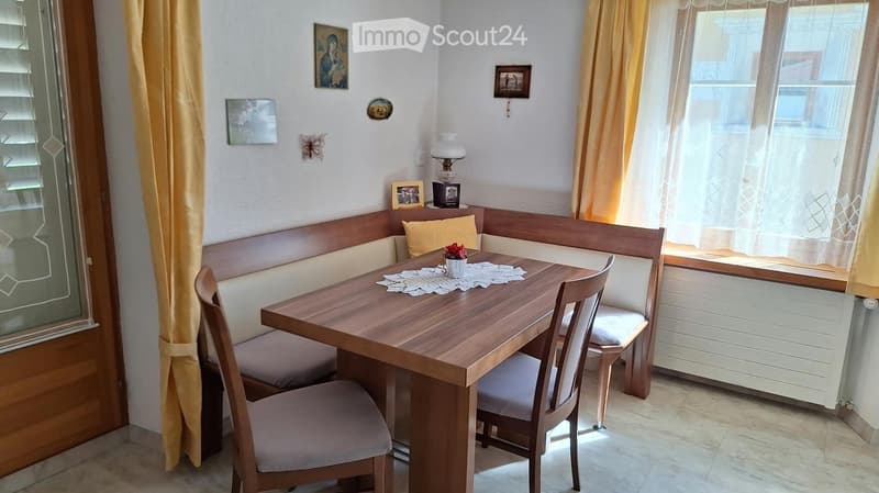 Cozy dining area with a wooden table, chairs, built-in bench seating, and a lamp on a small table.
