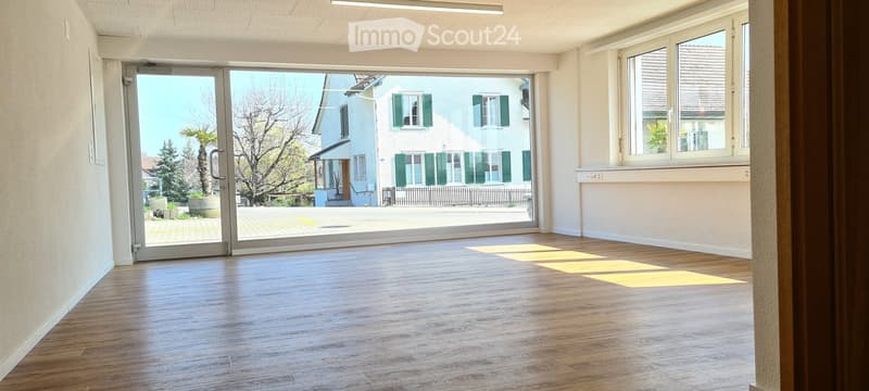 Empty room with wooden flooring, large glass sliding door leading outside, and white walls.