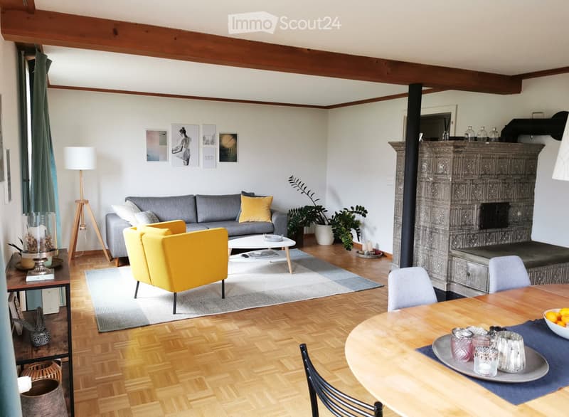 Living room with grey sofa, yellow armchair, coffee table, dining table, fireplace, and decorative items.
