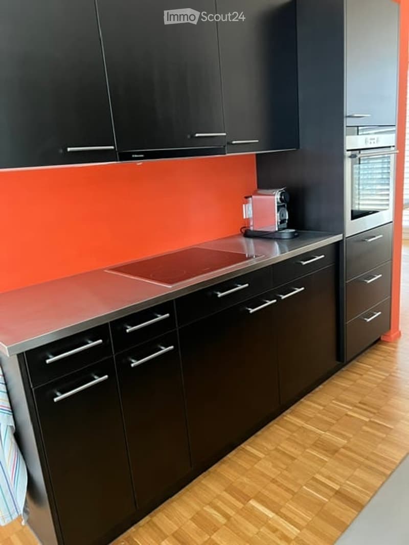 Modern kitchen with black cabinets, a stainless steel countertop, and a coffee maker on the counter.