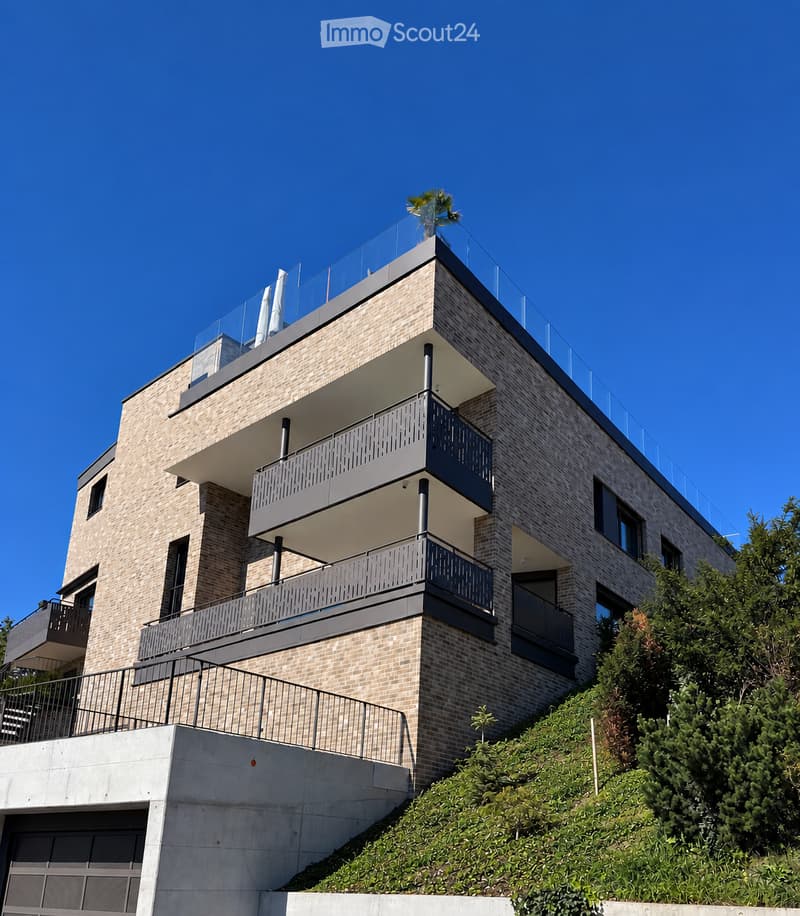 Modern multi-story building with brick facade, multiple balconies, and a garage at the base.