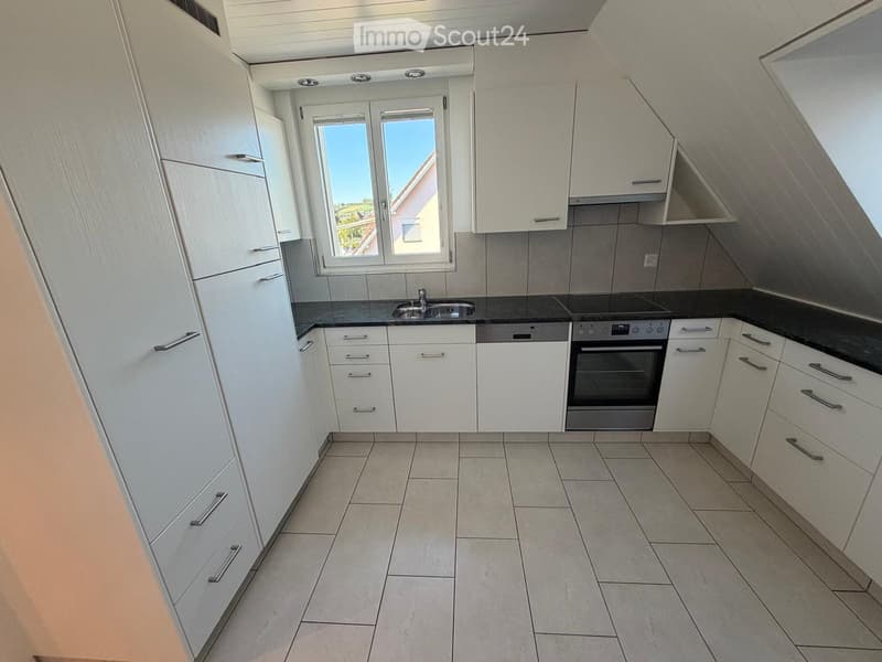 Modern kitchen with white cabinets, tiled floor, and stainless steel appliances including a sink and oven.