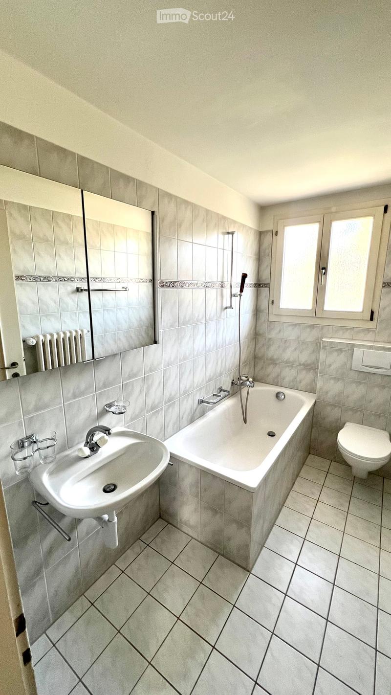 Bathroom with a sink, bathtub, toilet, mirror, and two cups on the sink counter.
