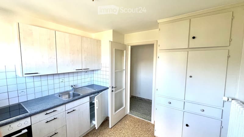 Modern kitchen with white cabinets, stainless steel sink, and built-in oven. The space features tiled backsplash and a neutral color palette.
