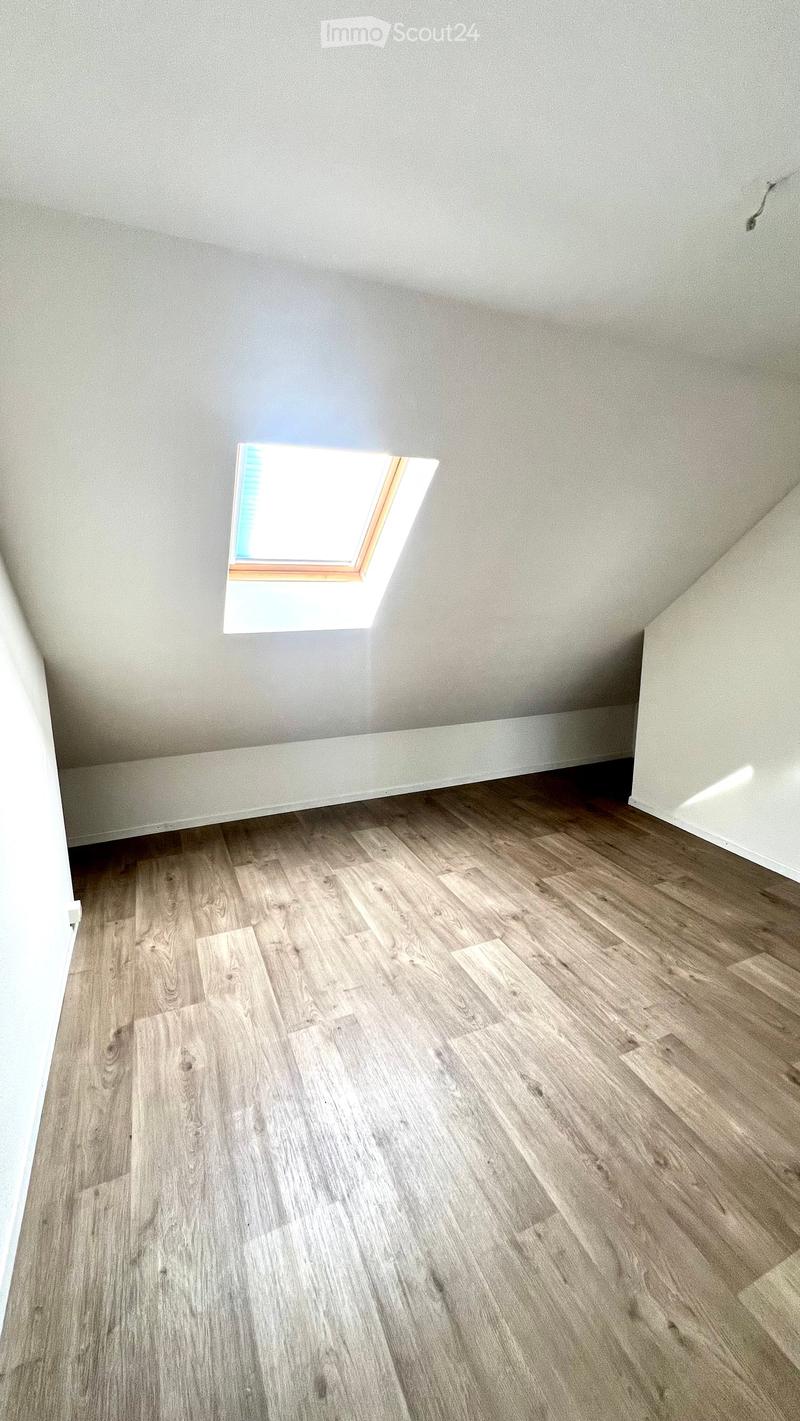 Empty room with wooden flooring and a skylight window in the ceiling.