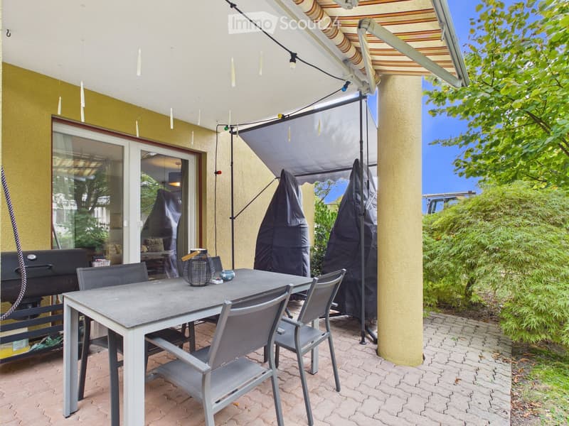 Outdoor patio with a table, chairs, barbecue, and covered seating area with a retractable awning.