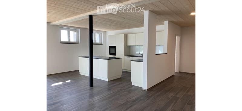 Modern kitchen with white cabinets, dark countertops, and wooden flooring.