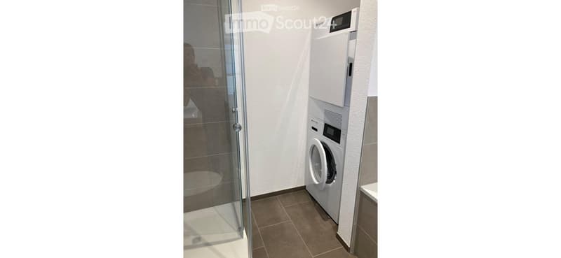 Modern bathroom with a glass-enclosed shower stall and a private washing machine unit.