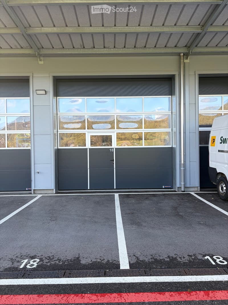 Garage with large roll-up door, windows, and a parking space marked with number 18.