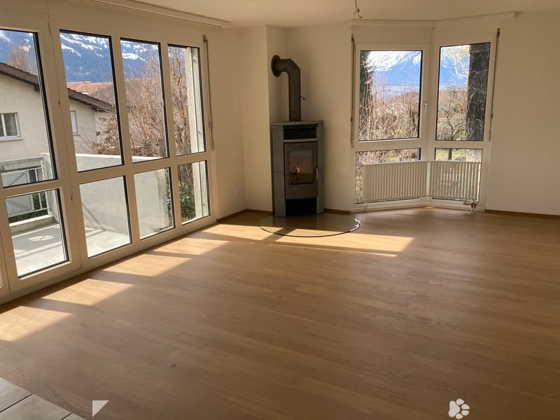 Empty room with wooden flooring, large windows, and a fireplace. No furniture or equipment present.