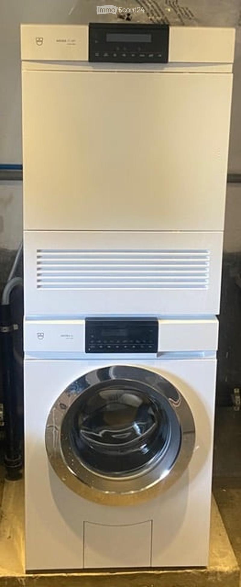 Modern white washing machine and dryer unit with digital control panels, placed on wooden flooring.