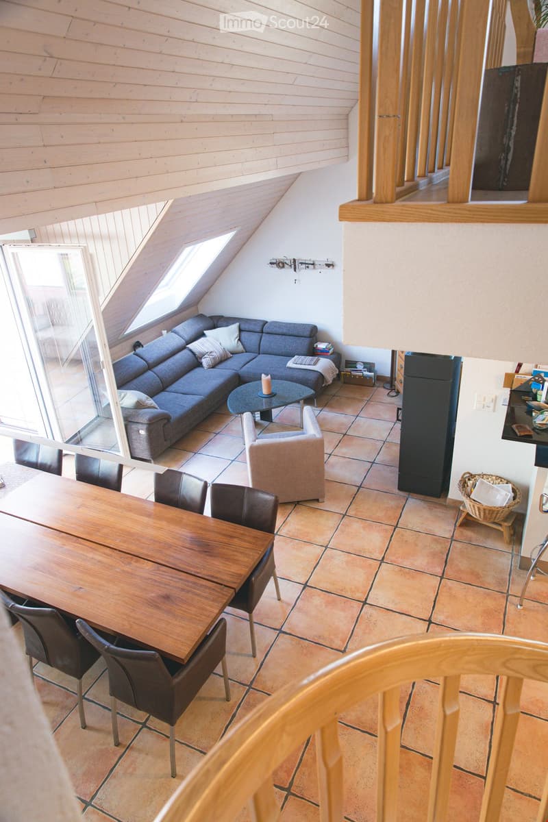Living room with a grey sectional sofa, coffee table, dining table with chairs, and a small side table with a basket.