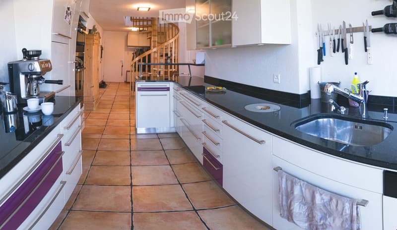 Modern kitchen with white cabinets, black countertops, stainless steel sink, coffee maker, and knife rack.