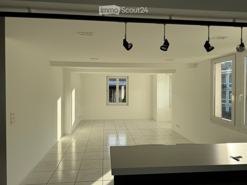 Empty room with white walls, tiled floor, and large windows. No furniture or equipment present.