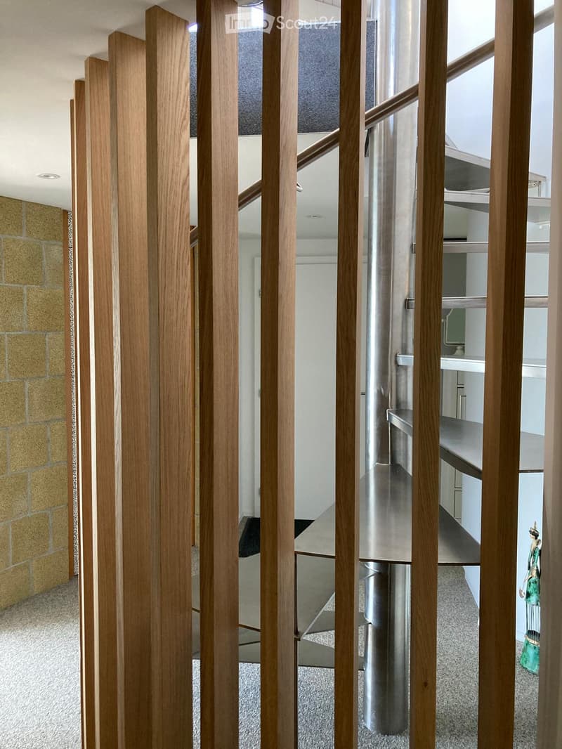 Modern hallway with wooden paneling, carpeted floor, and a view into a kitchen area with stainless steel appliances and white cabinets.