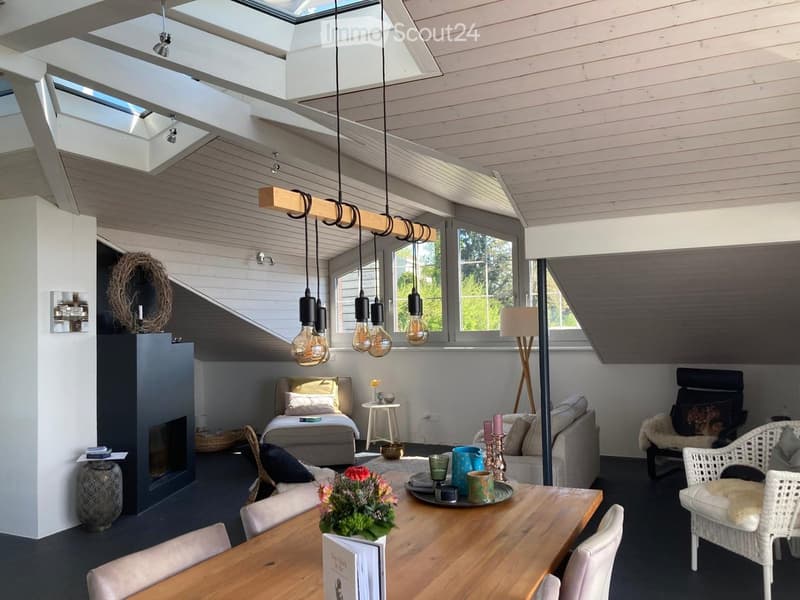 Bright, modern living space with a fireplace, sofa, dining table, and a cozy bed area. Features pendant lights, large windows, and a mix of contemporary and rustic decor.