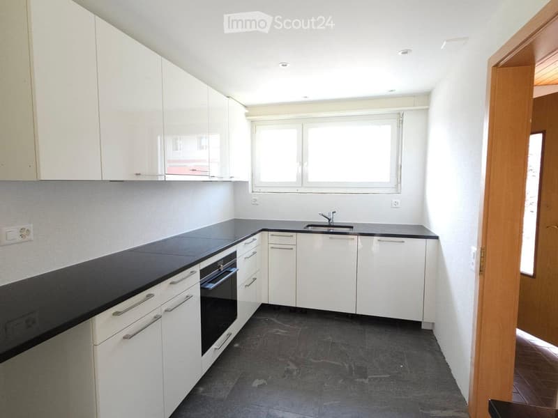 Modern kitchen with white cabinets, black countertops, and a sink. Features an oven and ample storage space.