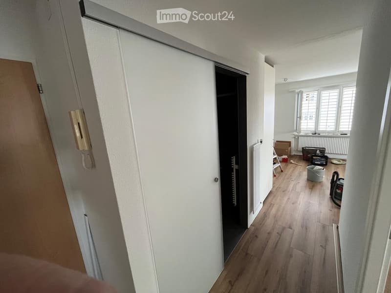 Empty room with wooden flooring, white walls, and a partially open door leading to another space. No furniture or equipment is visible.