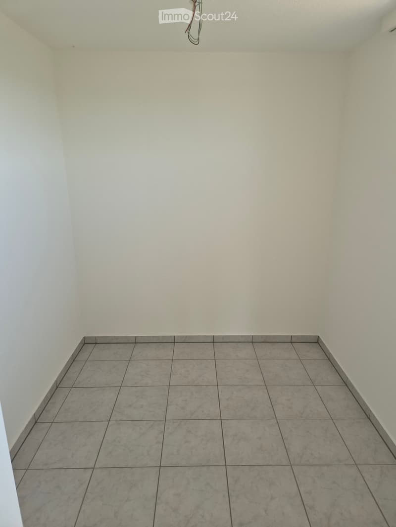 Empty room with light-colored tiled floor and white walls, no furniture or equipment visible.