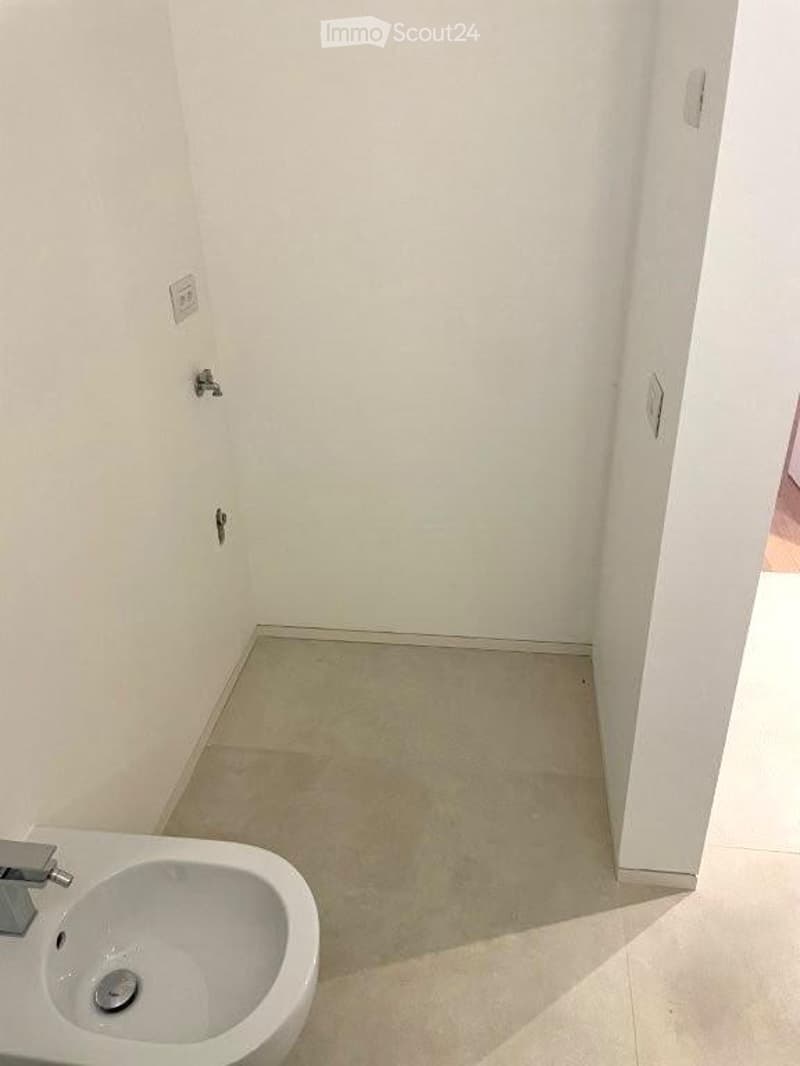 Empty bathroom with white walls, beige tiled floor, and a single sink fixture.