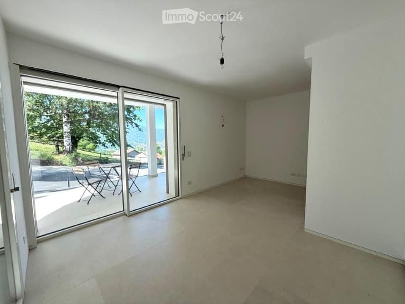 Empty room with large sliding glass doors leading to a patio, tiled floor, and white walls.