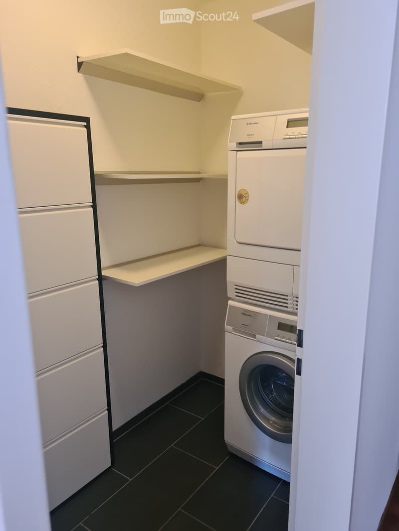 A small utility room with a washing machine, dishwasher, and built-in shelves.