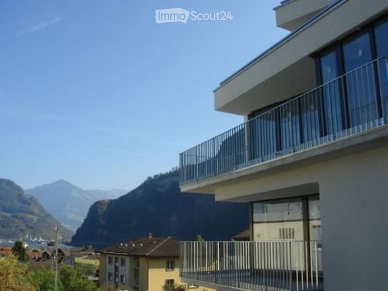 Modern multi-story building with large windows and balconies overlooking a scenic mountain view.