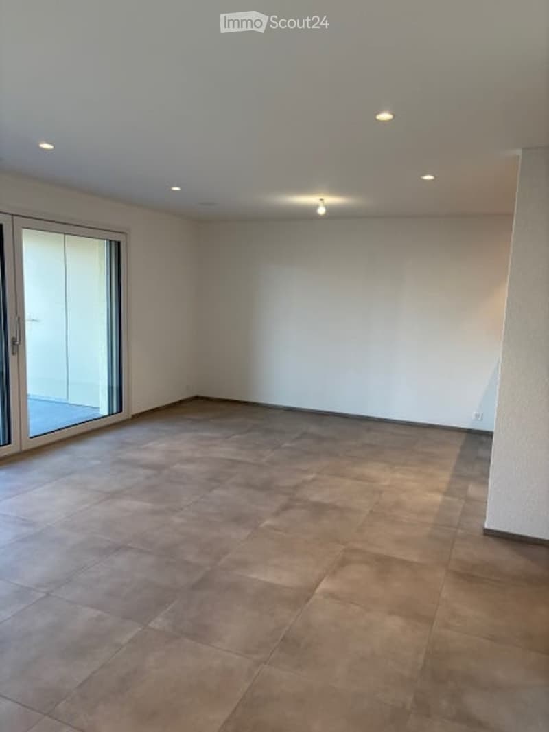 Empty room with tiled floor, white walls, and large glass sliding door leading to an outdoor area.