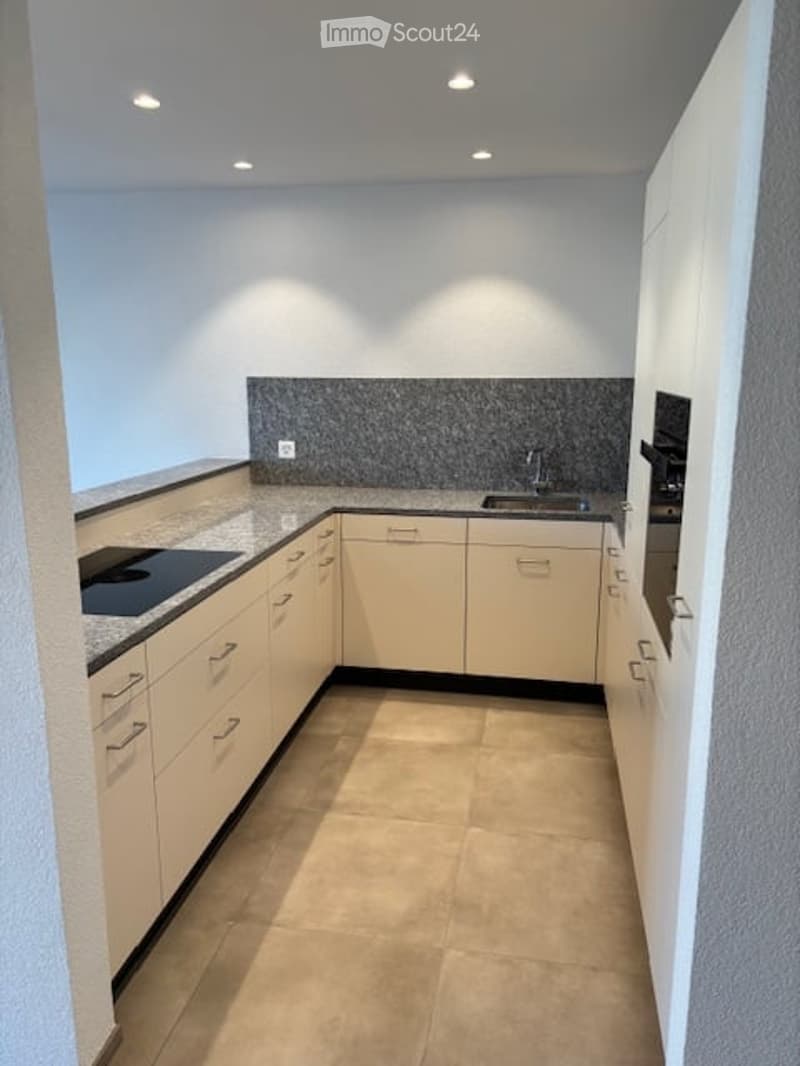 Modern kitchen with light-colored cabinets, granite countertop, built-in stove, and sink.