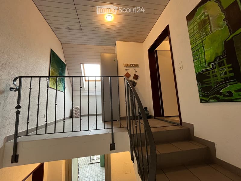 Staircase with metal railing, light fixture, and artwork on walls.