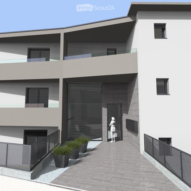 Modern two-story building with a balcony, large windows, and a glass entrance door. The ground floor features a paved area with potted plants and a metal fence.