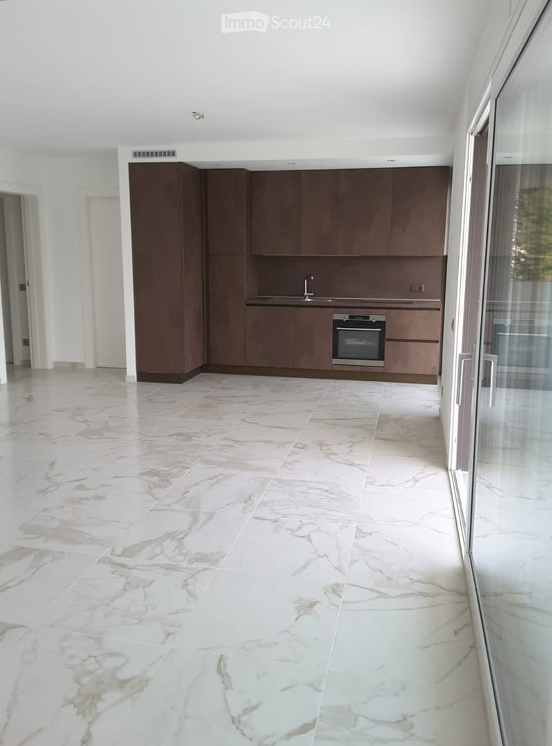 Modern kitchen with dark wood cabinets, marble flooring, and stainless steel appliances including a sink and oven.