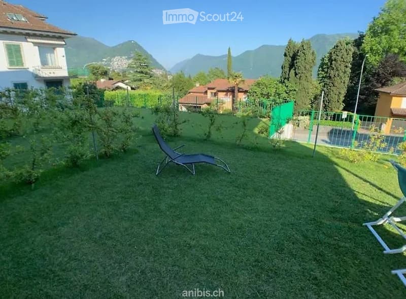 Well-maintained garden with green grass, lounge chairs, and a scenic mountain view in the background.