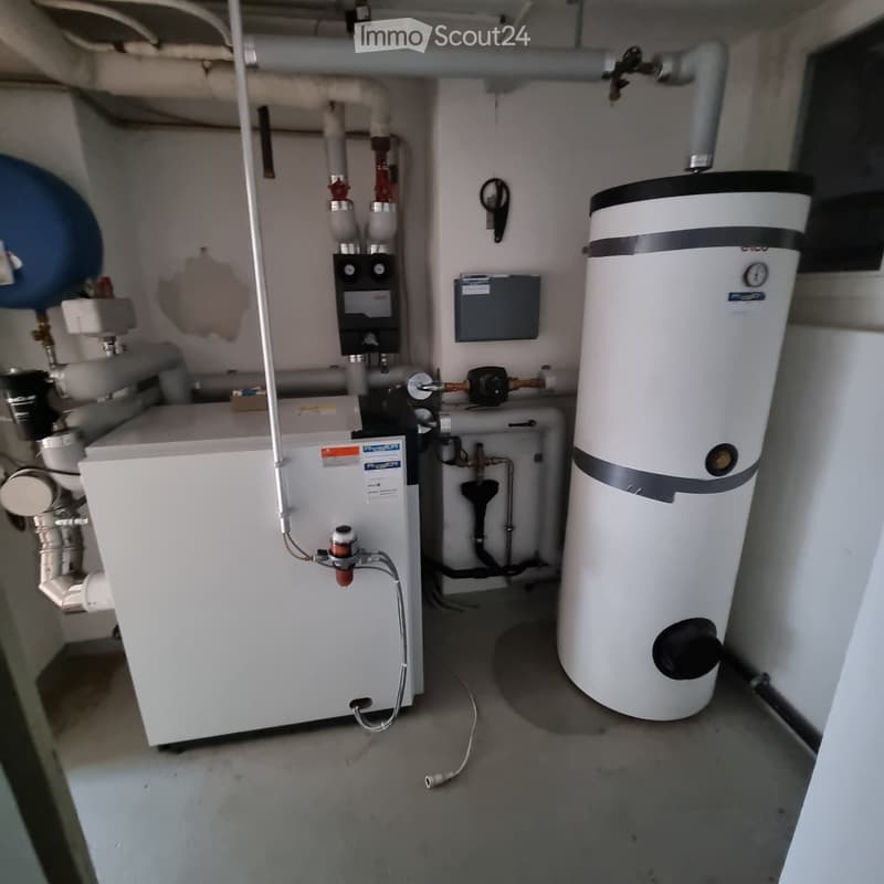 Utility room with a water heater, boiler, and various pipes and valves.