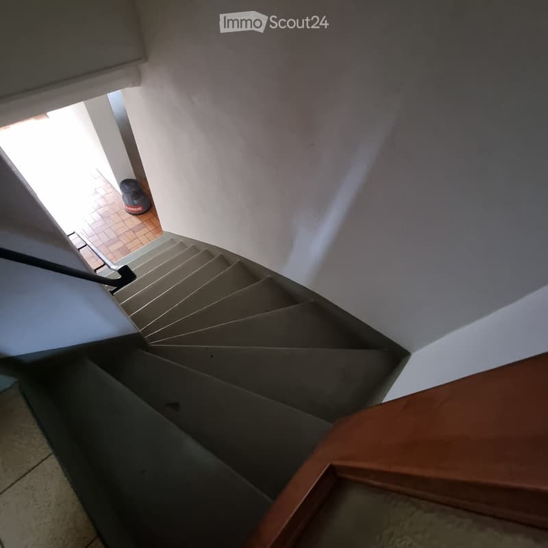 Staircase leading to an open area with tiled floor and visible railing.