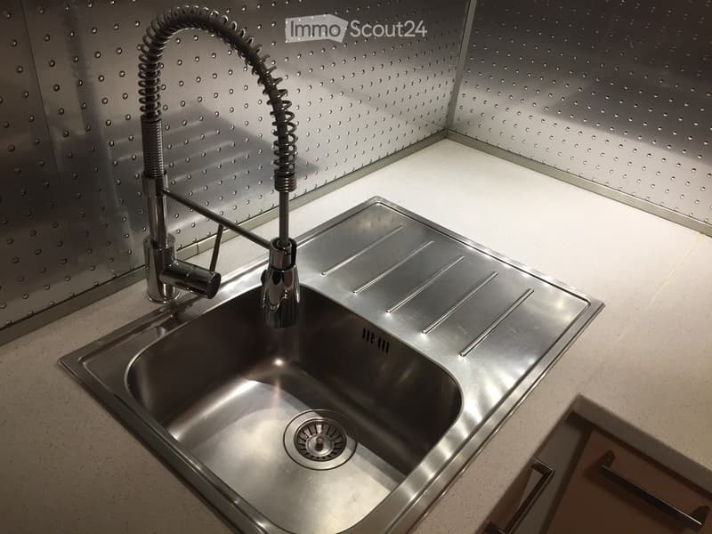 Modern kitchen sink with a sleek, stainless steel faucet and a perforated metal backsplash.