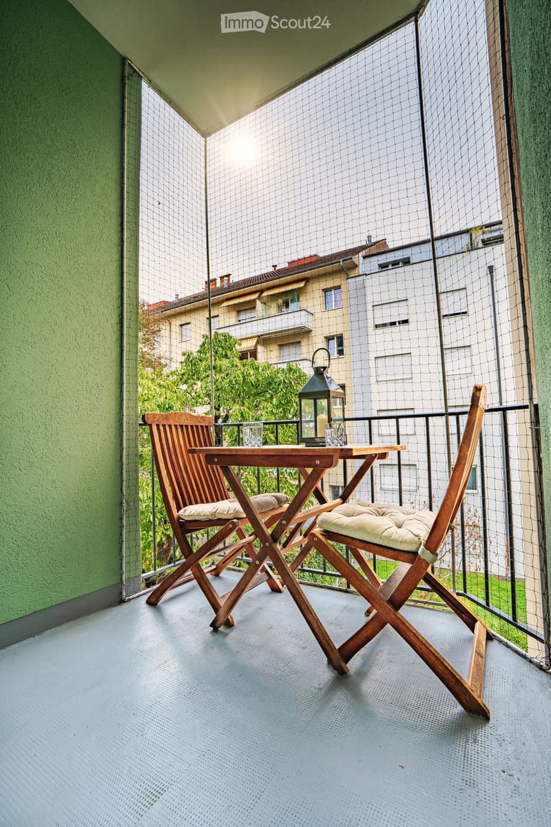 Balcony with a small wooden table, two wooden chairs with cushions, and a lantern in the center.