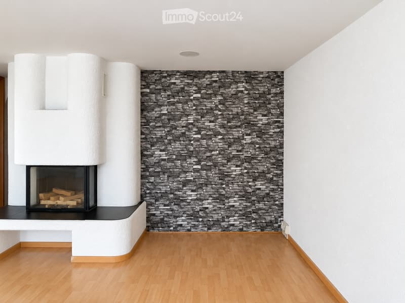 Modern living room with a stone fireplace, wooden flooring, and white walls.