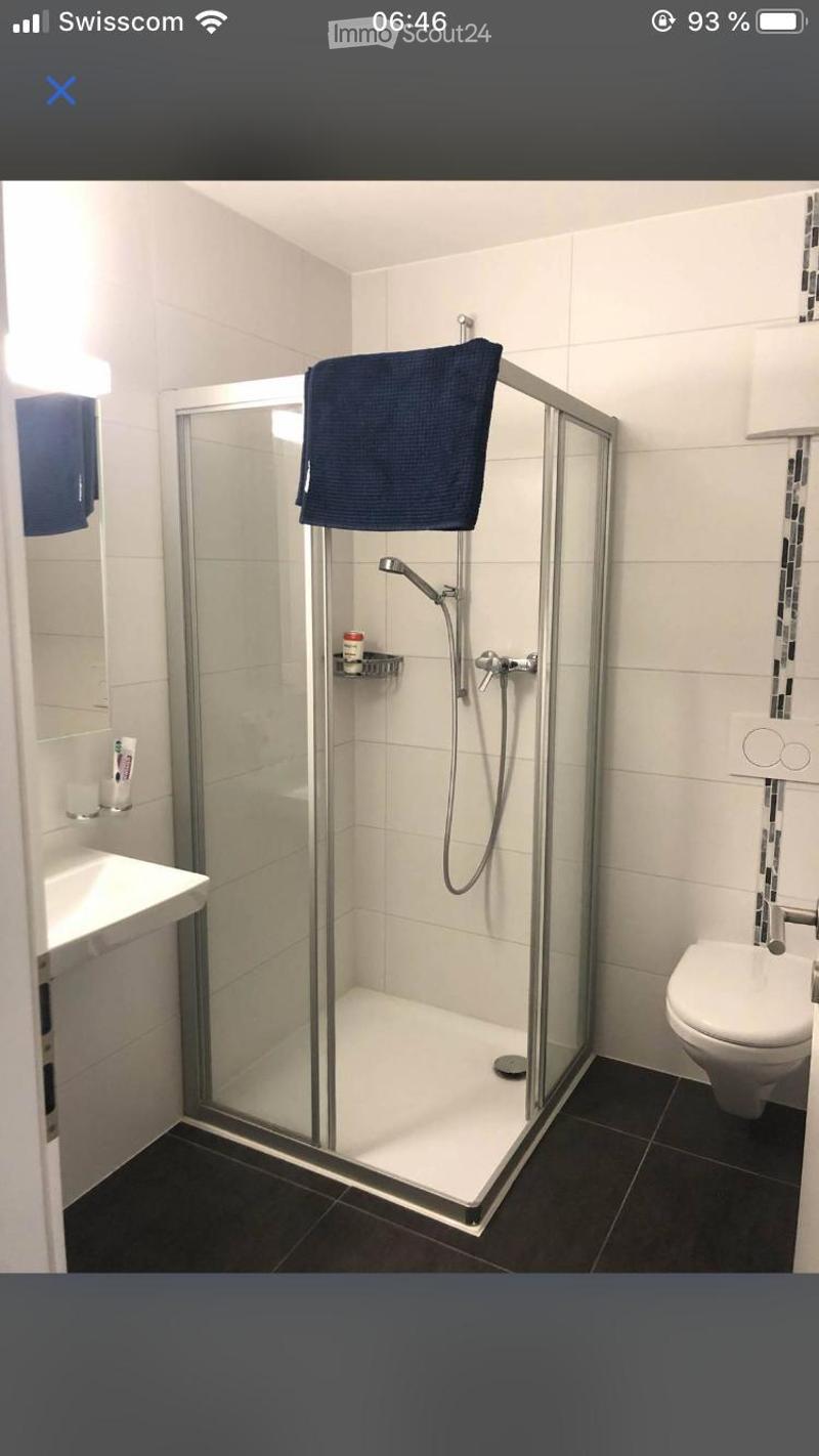 Modern bathroom with a glass-enclosed shower, toilet, sink, and a towel hanging on the shower door.