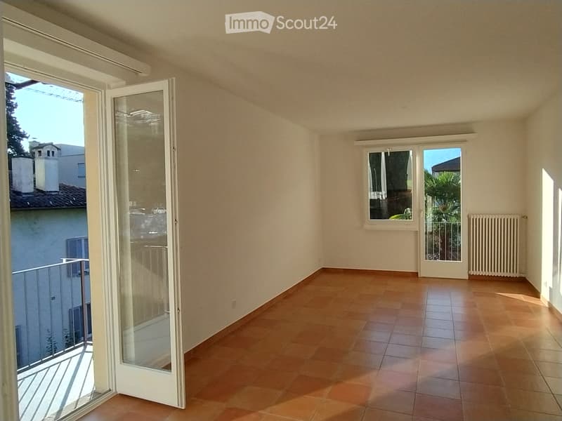 Hallway with beige walls, tiled floor, multiple windows, radiator, and a skylight at the top.