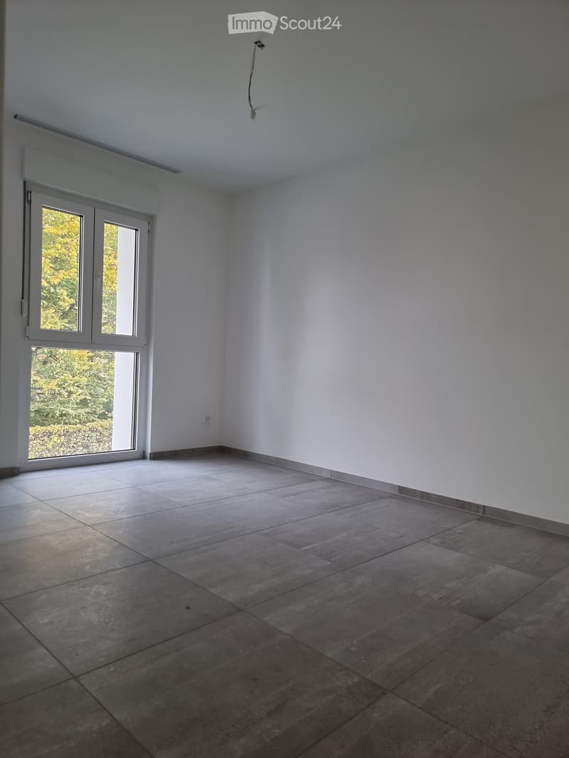 Empty room with tiled floor, white walls, and large sliding glass door leading to outdoor area.