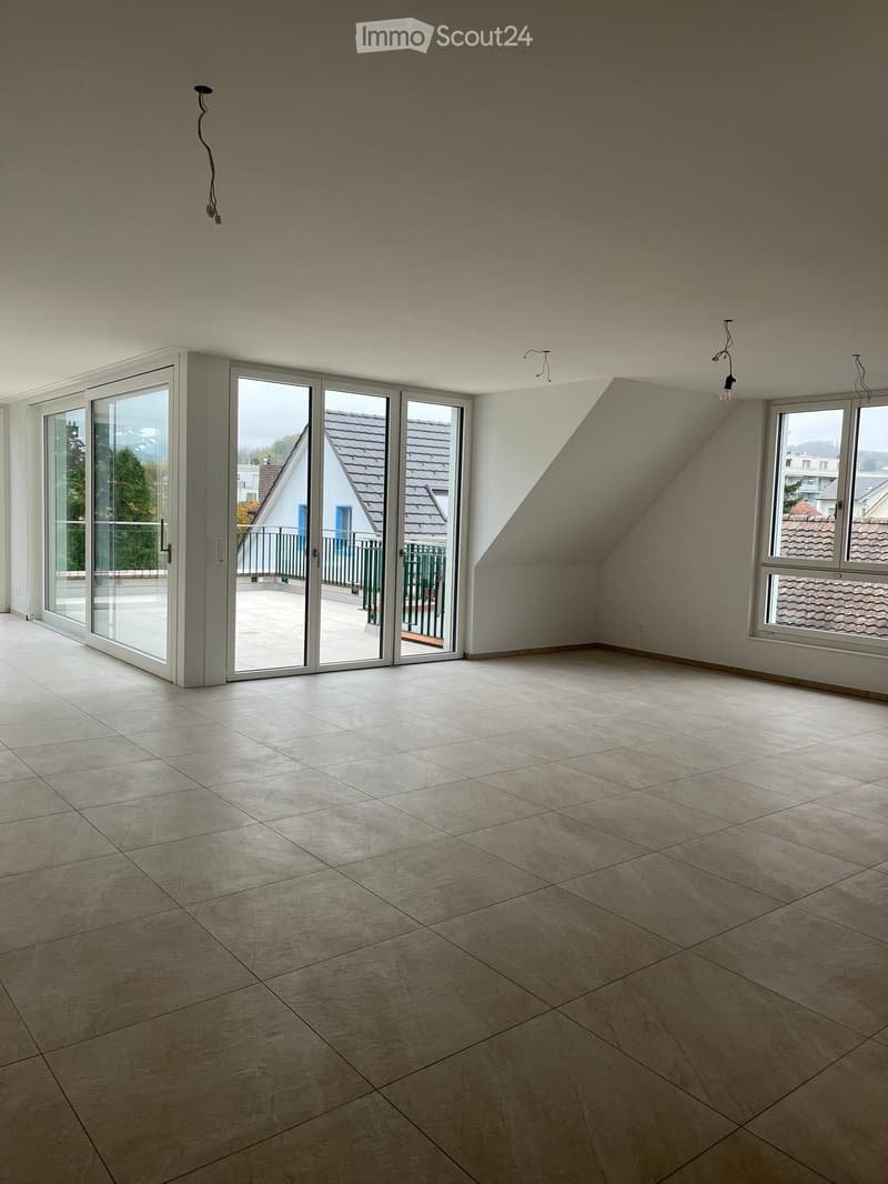 Empty room with tiled floor, large windows, and sliding glass doors leading to a balcony.
