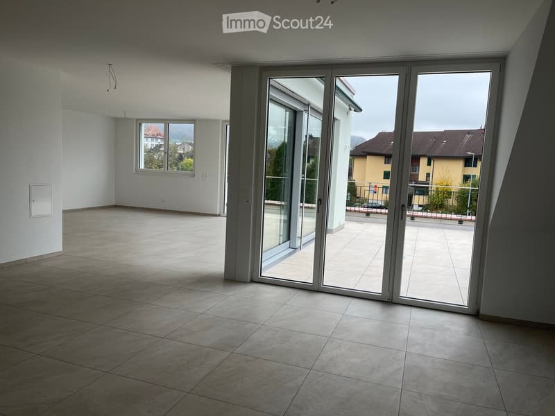 Empty room with tiled floor, large sliding glass doors leading to a balcony, and a window with a view of the neighborhood.
