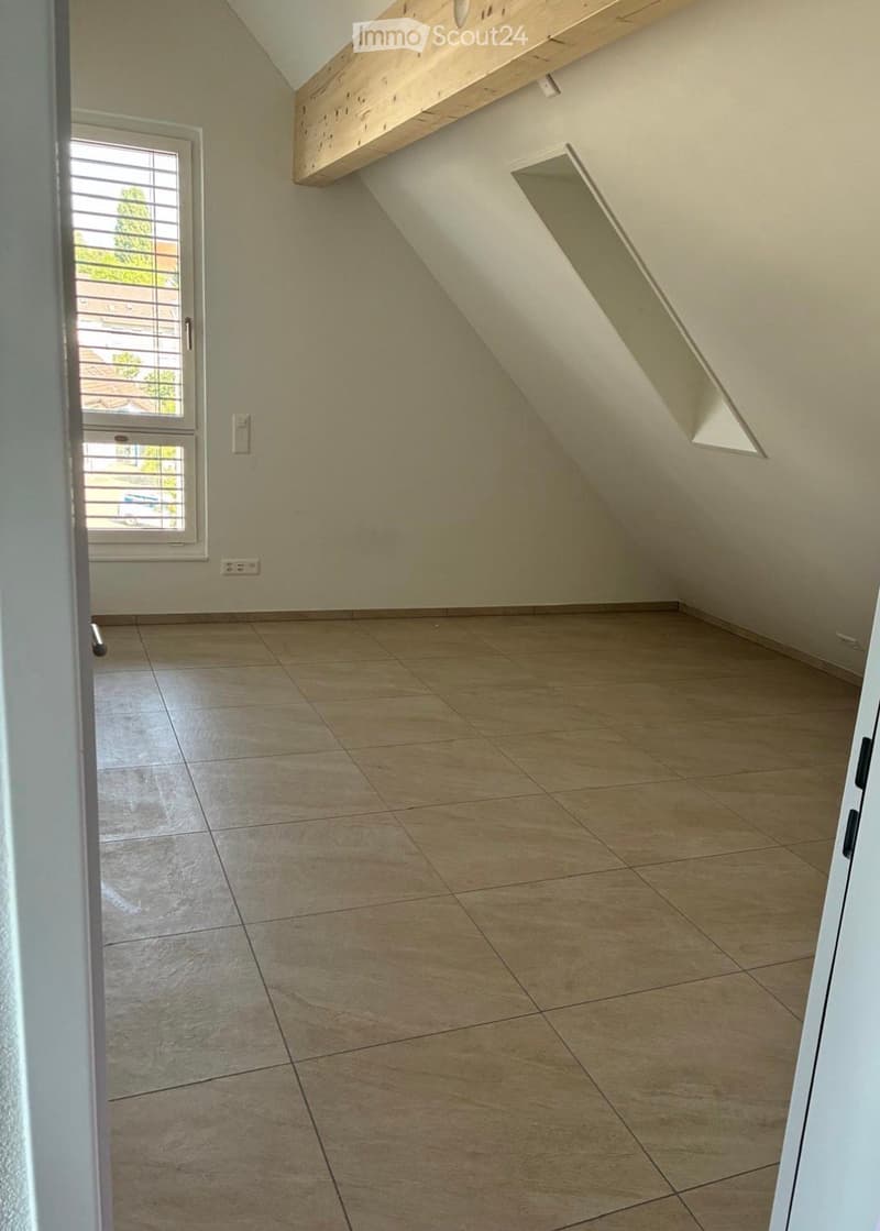 Empty room with tiled floor, slanted ceiling, window with blinds, and built-in shelf.